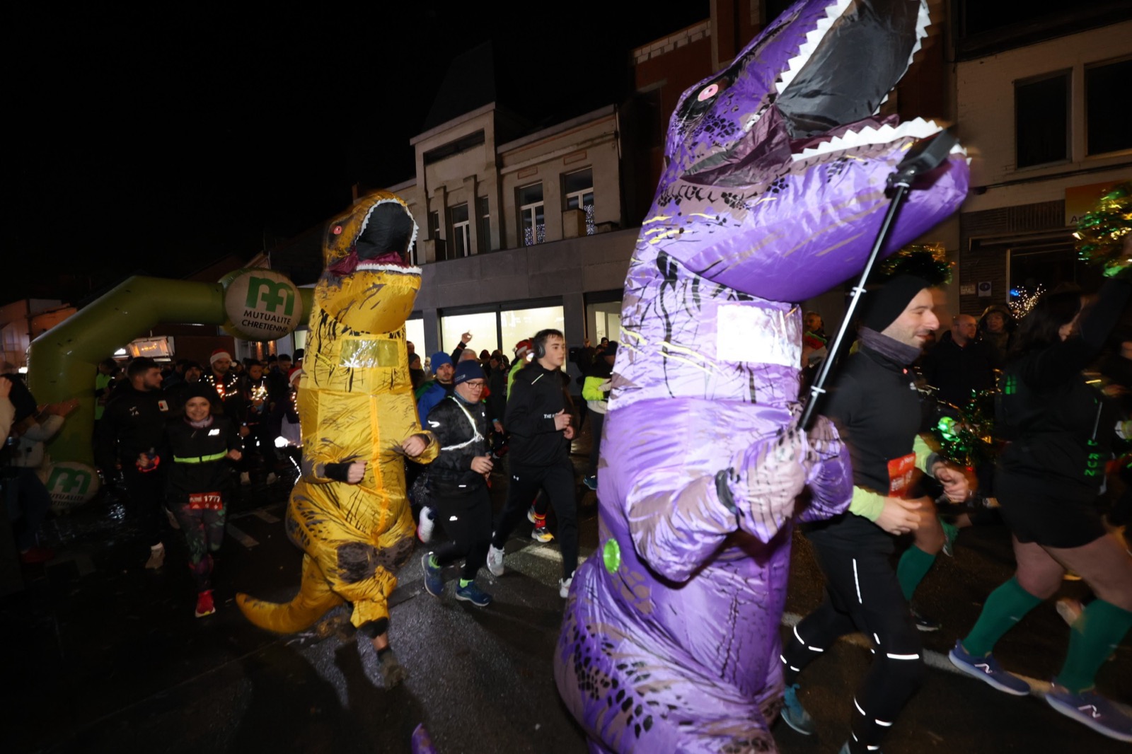 Deux coureurs en costume gonflable de dinosaure dans la rue